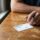 Blue Cross Blue Shield insurance card on kitchen table with hand and pen, representing family preparing to verify detox coverage in New Hampshire
