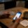Parent's hands holding insurance card and phone on kitchen table while researching detox treatment options